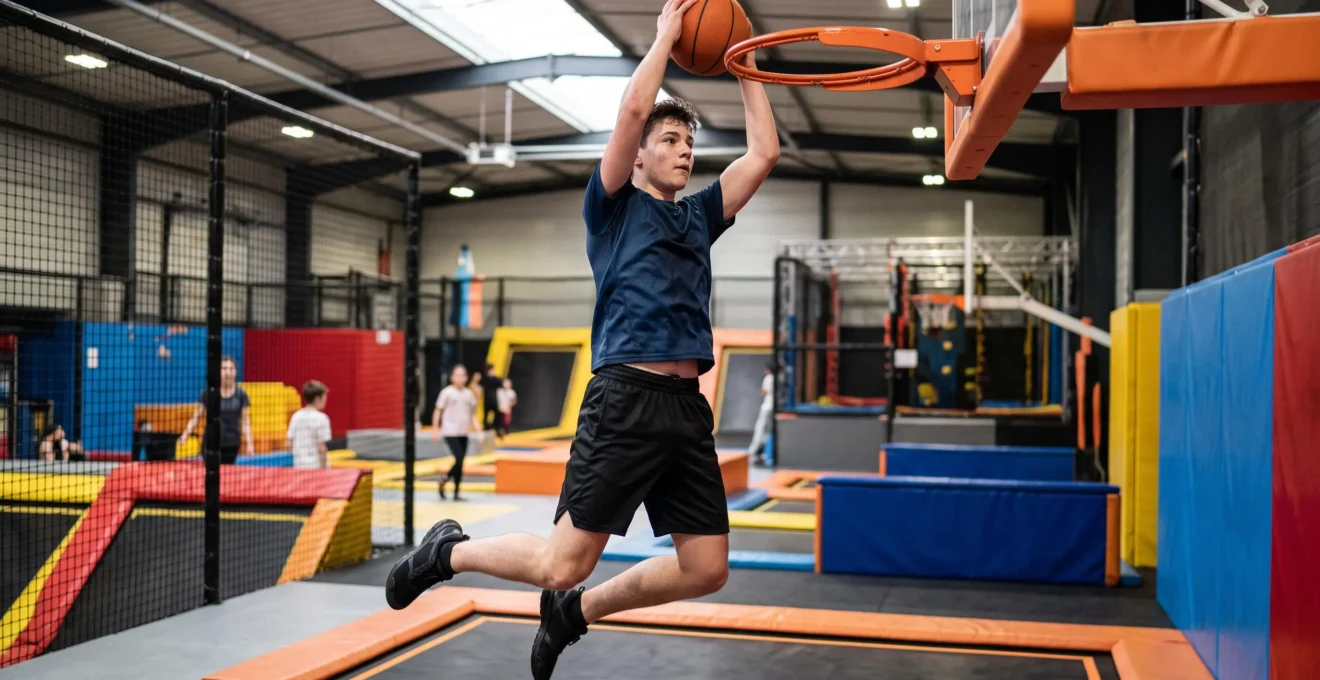 Adolescent effectuant un slam dunk sur un panier de basket installé au-dessus d'un trampoline dans un trampoline park